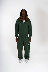 Ensemble Cynique vert sapin. Zipper et pantalon assortis avec logo brodé blanc, coupe oversize et finition premium. L’équilibre parfait entre confort, minimalisme et esthétique street.