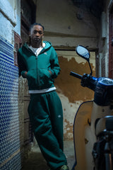 Total look Cynique vert sapin dans les ruelles marocaines. Ensemble streetwear oversized, logo brodé discret, ambiance locale et urbaine, toujours fidèle à l’ADN de la marque.