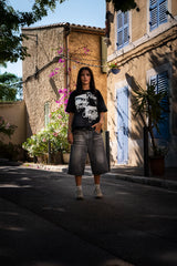 Look streetwear Cynique en extérieur. Jort gris en denim, t-shirt Created. Coupe large, style brut, minimaliste, pensé pour le réel.