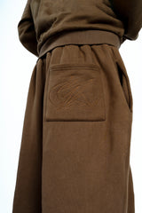 Détail du pantalon large marron Cynique. Broderie ton sur ton du logo iconique sur la poche arrière pour un look minimaliste et travaillé.