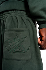 Détail broderie du jogging vert Cynique. Une finition soignée et un logo ton sur ton pour un look minimaliste et affirmé.