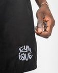 Détail du logo Cynique brodé sur le maillot de bain noir. Short minimaliste, brut, streetwear. Focus sur la finition et l’attitude.