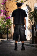 Jort noir Cynique en denim épais. Coupe large, logo brodé. Un short streetwear brut et massif.