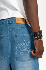 Détail du Jort bleu Cynique. Broderie logo arrière, patch cuir. Short en jean brut, solide, minimaliste, pensé pour durer avec style.