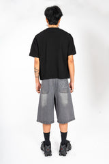 Jort gris Cynique en denim vu de dos. Broderie logo arrière, coupe large. Short en jean brut et solide, taillé pour durer, style minimaliste.