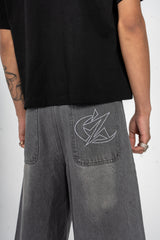 Détail du Jort gris Cynique. Broderie logo arrière, denim brut, coupe large. Short minimaliste et solide, pensé pour le style et le réel.