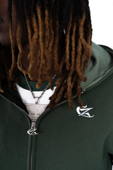 Zoom sur le hoodie Cynique vert sapin, détails soignés : broderie blanche discrète et curseur de fermeture éclaire customisé. Pièce minimaliste mais travaillée, à l’image du streetwear Cynique.