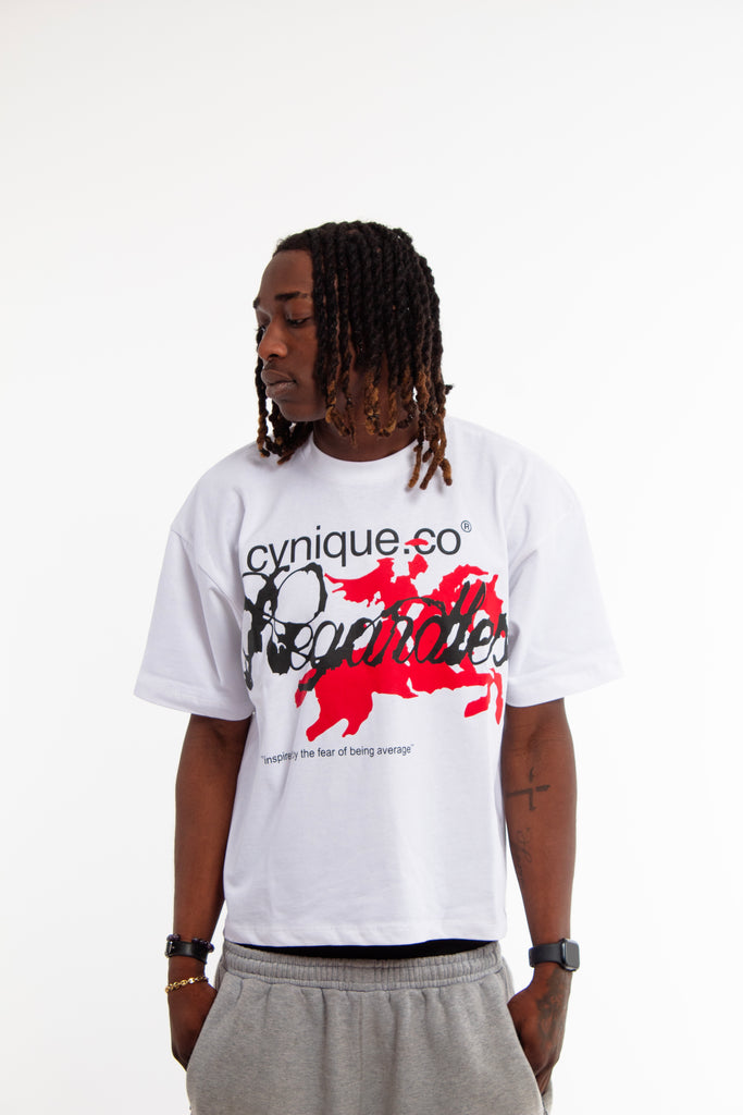Male model wearing Cynique Regardless Tee — oversized white graphic T-shirt with red horse artwork and bold typography, styled with gray sweatpants in studio