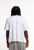 Back view of male model wearing Cynique Regardless Tee — plain white oversized T-shirt in soft cotton with relaxed fit, shown from behind in studio setting