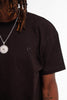 Chest detail of Cynique Vanta Black Tee — tonal embroidered logo on heavyweight cotton fabric, styled with chain pendant necklace in a studio setting