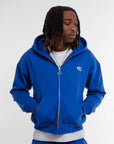 Mannequin homme portant un hoodie zippé et jogging bleu électrique Cynique en coton 450 GSM. Coupe oversize, logo brodé blanc côté cœur, style streetwear minimaliste.