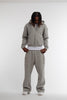Male model wearing Cynique Basic Gray tracksuit — boxy fit zip hoodie and oversized cotton joggers styled with white sneakers in minimal studio setting