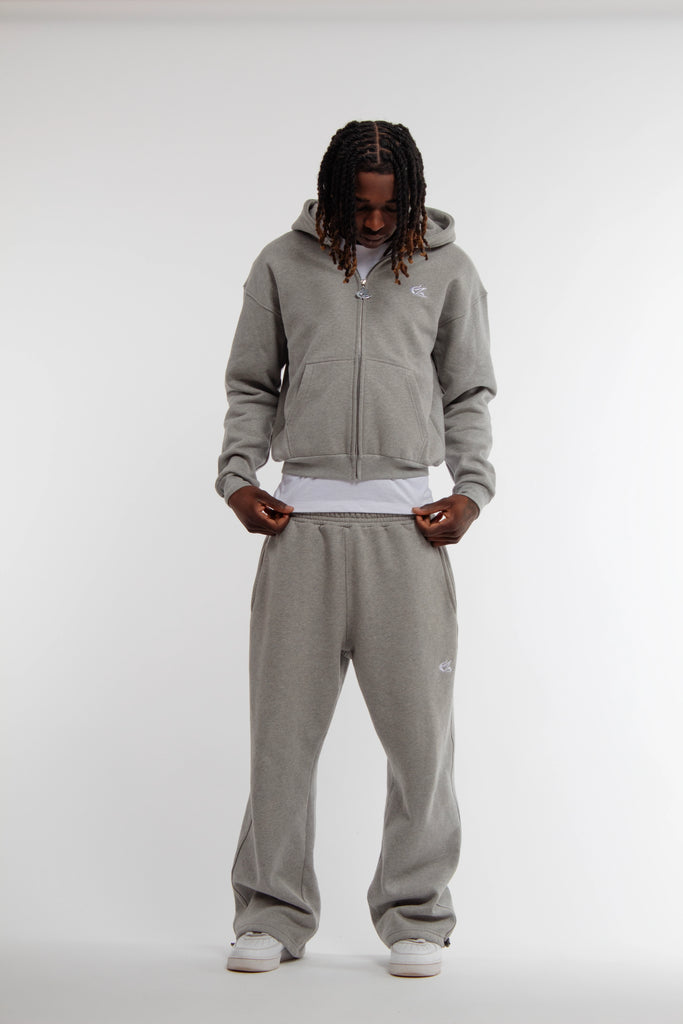 Mannequin homme portant un ensemble hoodie zippé et jogging gris clair Cynique. Coupe oversize, coton 450 GSM, logo brodé blanc, tenue streetwear minimaliste.