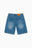 Jort bleu Cynique en denim. Coupe large, patch cuir et broderie logo au dos. Short en jean brut, solide, minimaliste, pensé pour durer.