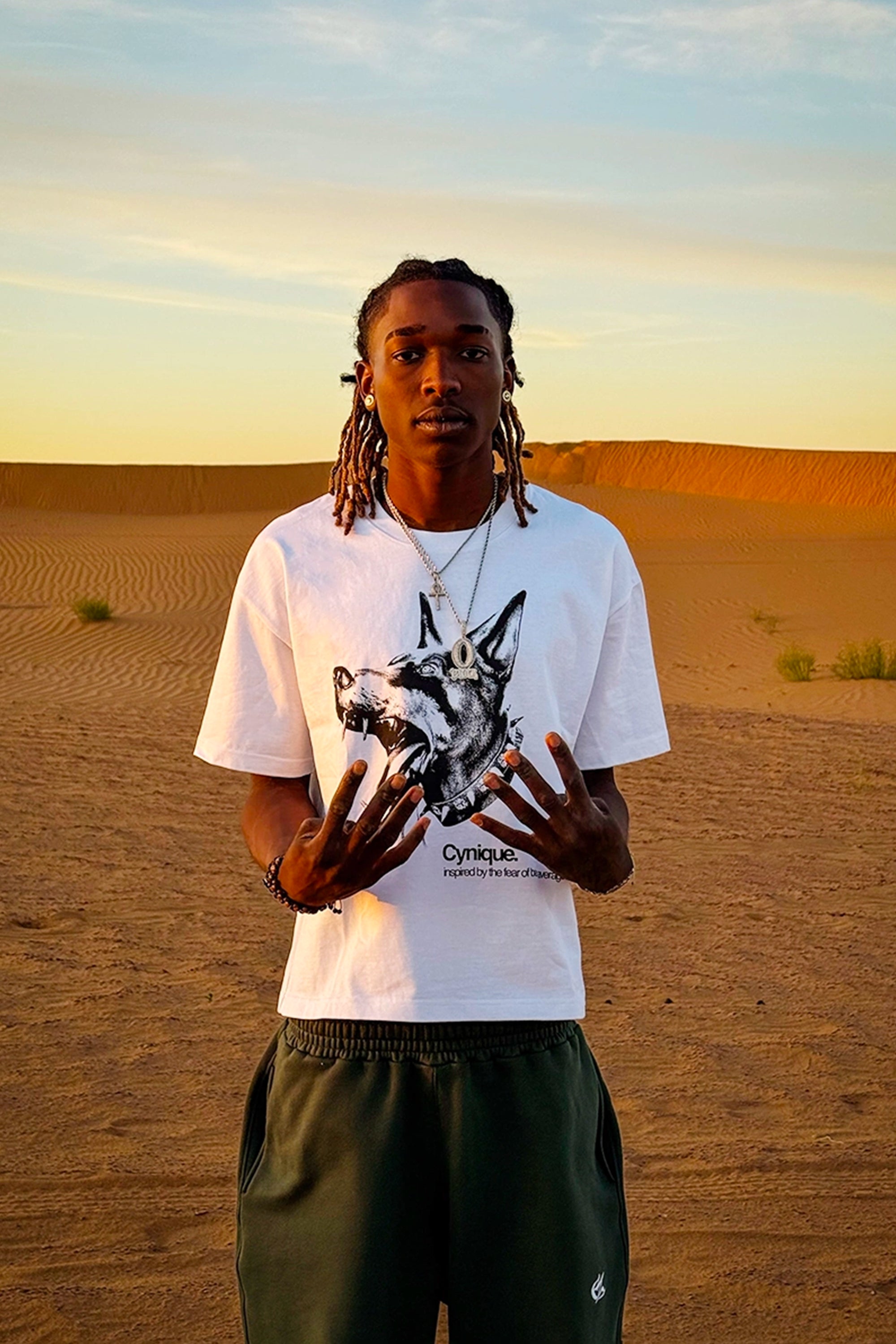T-shirt Cynique blanc avec imprimé Doberman. Look brutal et minimaliste au cœur des dunes, inspiré par la peur d’être moyen.