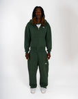 Ensemble Cynique vert sapin. Zipper et pantalon assortis avec logo brodé blanc, coupe oversize et finition premium. L’équilibre parfait entre confort, minimalisme et esthétique street.
