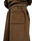 Détail du pantalon large marron Cynique. Broderie ton sur ton du logo iconique sur la poche arrière pour un look minimaliste et travaillé.