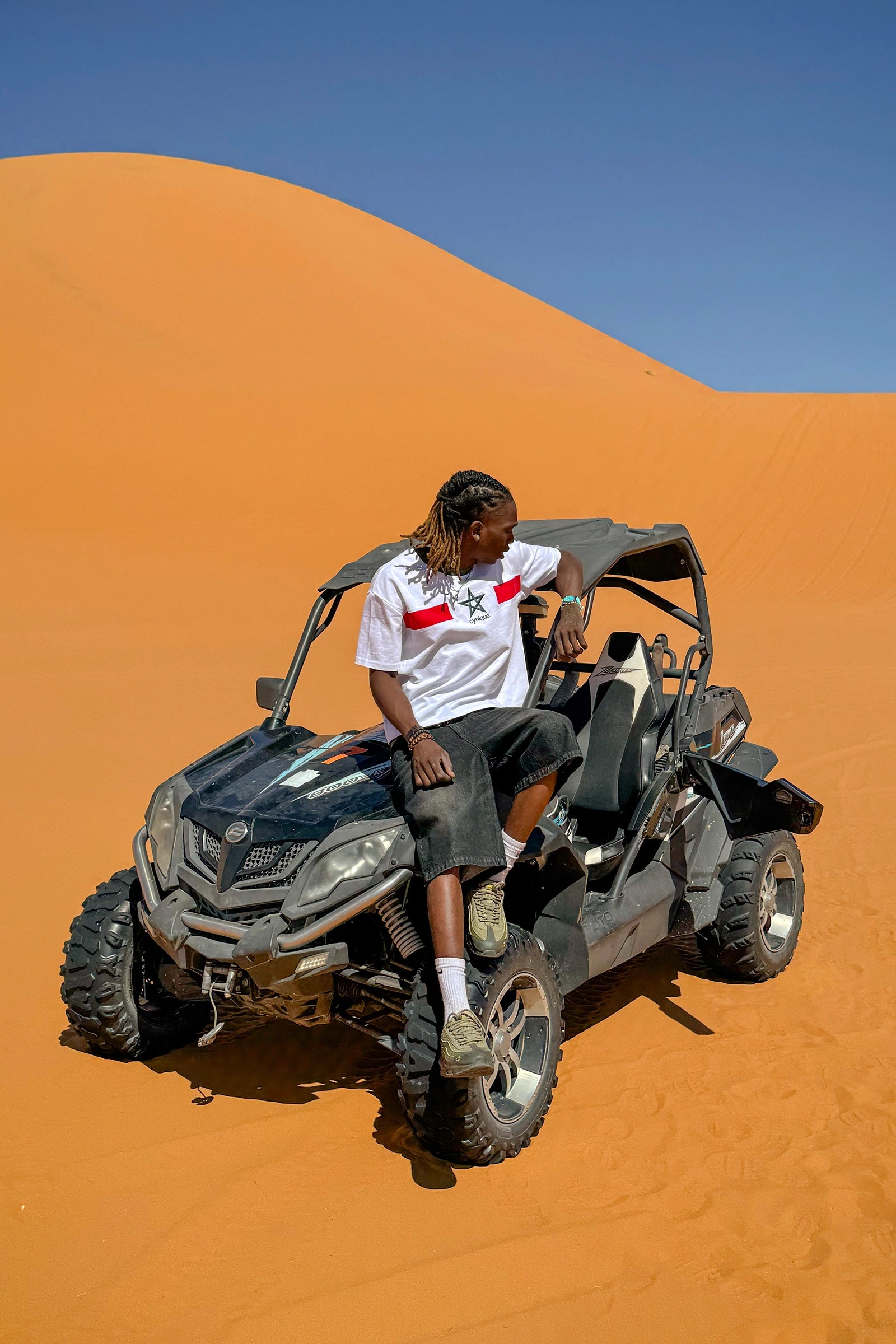 Jort noir Cynique en denim porté dans le désert. Short en jean brut, coupe large, style minimaliste et solide. Pensé pour durer, partout.