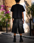 Jort noir Cynique en denim épais. Coupe large, logo brodé. Un short streetwear brut et massif.