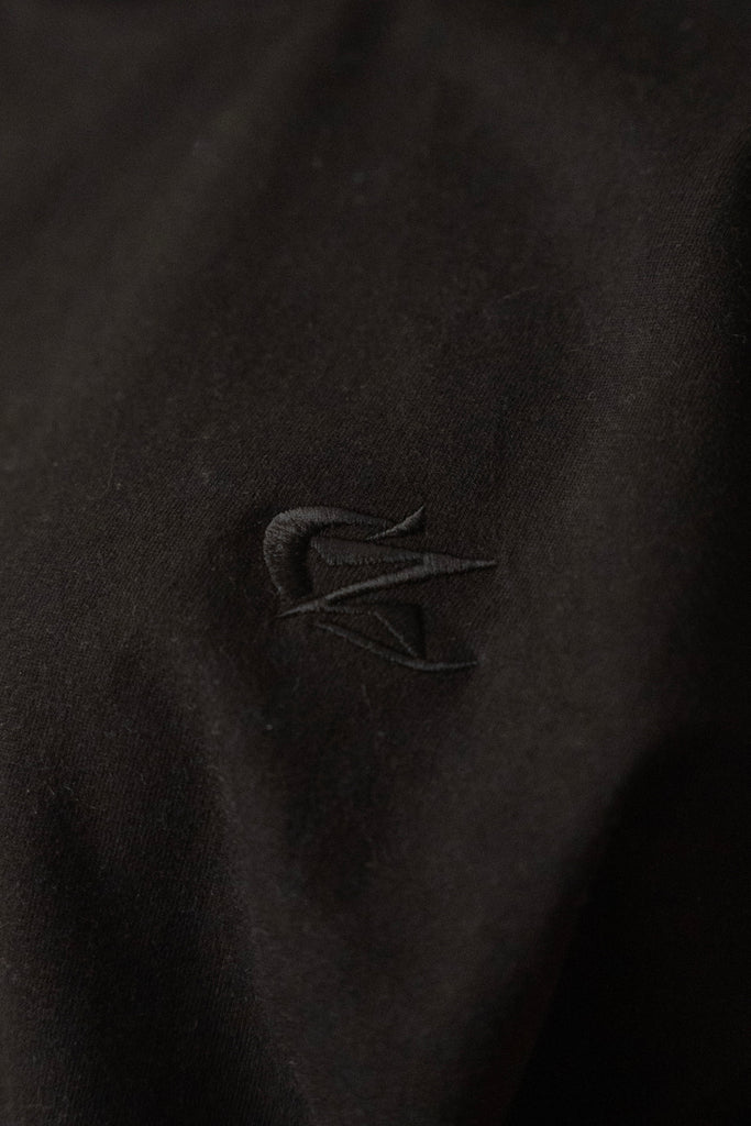 Close-up of tonal embroidered Cynique logo on Vanta Black Tee — detailed view of black-on-black stitching on 100% cotton streetwear T-shirt