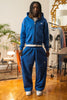 Full-body view of model wearing Cynique Basic Blue tracksuit — oversized hoodie and joggers in 100% cotton, styled with white sneakers in modern interior