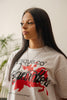 Close-up of female model wearing Cynique Regardless Tee — white oversized graphic T-shirt with red horse print and inspirational quote, styled with silver pendant