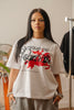 Female model wearing Cynique Regardless Tee — white oversized T-shirt featuring red horse silhouette and motivational quote, styled with gray sweatpants indoors