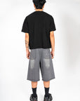 Jort gris Cynique en denim vu de dos. Broderie logo arrière, coupe large. Short en jean brut et solide, taillé pour durer, style minimaliste.