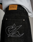 Zoom sur le jort noir Cynique. Logo brodé et patch cuir signature. Denim épais et brut, conçu pour durer.